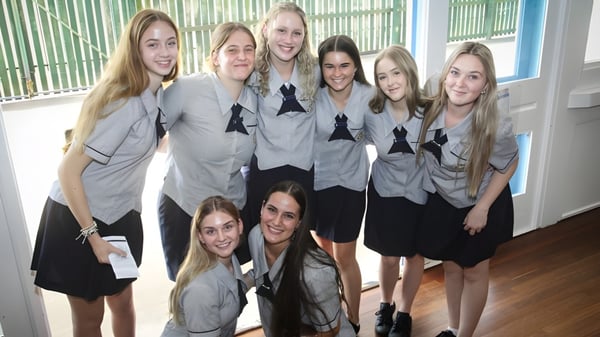 Un grupo de estudiantes de la Bundaberg State High School se encuentra juntos en una habitación con paredes de rayas verde y azul.