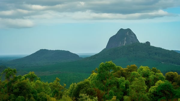 El paisaje natural con bosques verdes y formaciones rocosas distintivas cerca de la Burnie High School bajo un cielo nublado.