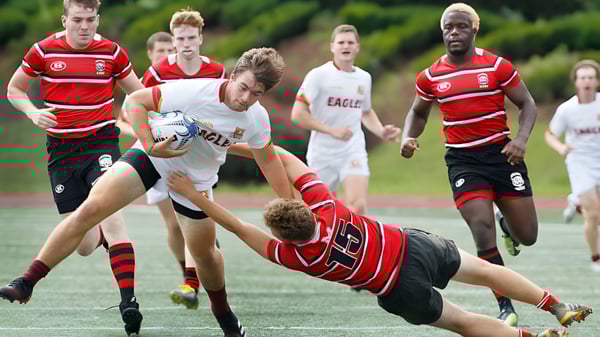 Estudiantes de la Burnie High School juegan un partido de rugby en el campo deportivo con jugadores en camisetas rojas y blancas.