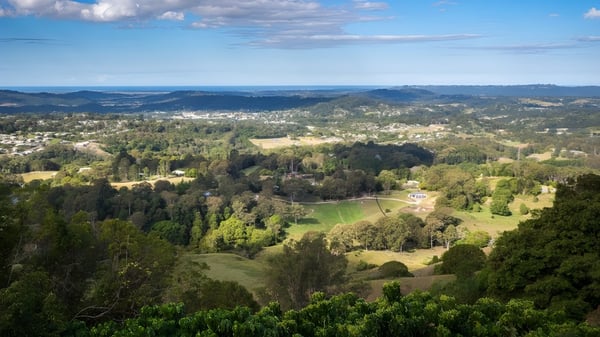 Paisaje verde con colinas, bosques y una pequeña ciudad al fondo, cerca de la Burnside State High School.