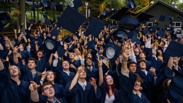 Graduados del Burpengary State Secondary College celebran al aire libre su ceremonia de graduación con togas y birretes negros.