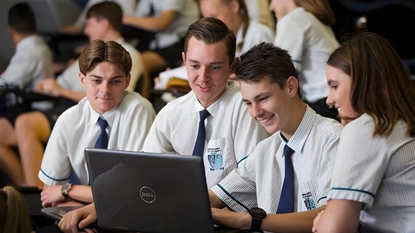 Un grupo de estudiantes en uniformes escolares trabaja juntos en una laptop en el Burpengary State Secondary College.