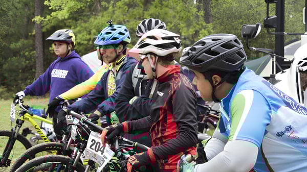 Un grupo de alumnos de la Bush Post Primary School está de pie con bicicletas y ropa de protección en un bosque.