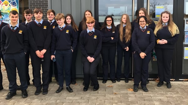 Un grupo de estudiantes de la Cabinteely Community School está frente a un edificio de ladrillo.