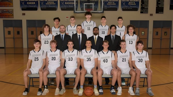 El equipo de baloncesto de la Cactus Shadows High School posa junto a los entrenadores en el gimnasio.