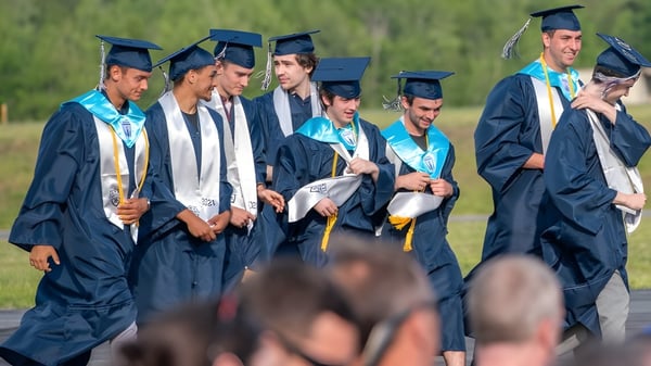 Un grupo de graduados en togas azules y blancas está reunido en el campus de la Cairns State High School.