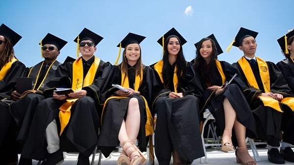 Las graduadas y graduados de la California State University Long Beach están juntos en ropa de graduación celebrando su éxito bajo un cielo azul.