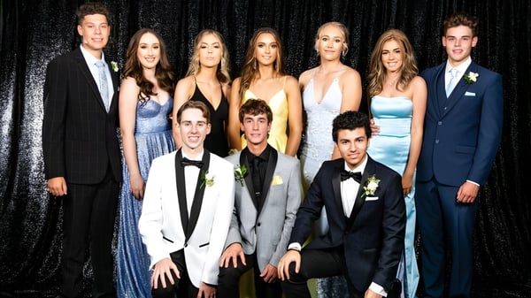 Un grupo de personas posa en un evento formal frente a un fondo negro en la Cambridge High School.