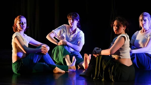 Un grupo de alumnas y alumnos de la Cambridge School of Weston se presenta en un escenario con iluminación colorida.