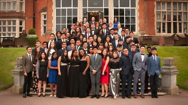 Un grupo de estudiantes del Cambridge Tutors College se reúne formalmente frente a un histórico edificio de ladrillo.