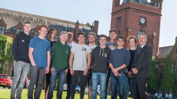 Un grupo de estudiantes está frente a un edificio de ladrillo con torre del reloj en el campus del Campbell College.
