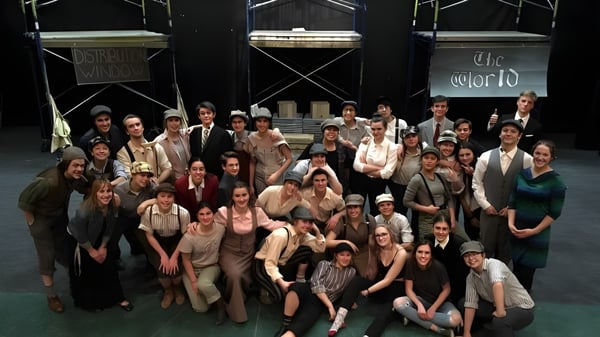 Estudiantes de la Canmore Collegiate High School se presentan en un escenario frente a un fondo con la inscripción The World.