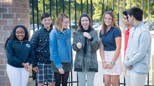 Un grupo de estudiantes se encuentra frente a un edificio de ladrillo en el campus de Canterbury High School.