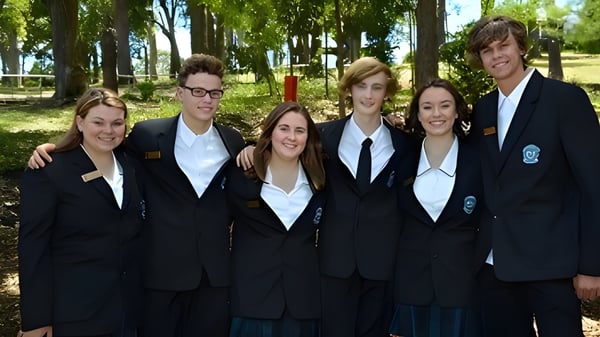 Un grupo de estudiantes de Cardiff High School está en uniformes escolares en un bosque y posan para una foto.
