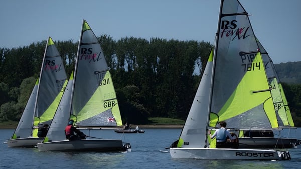 Los veleros navegan sobre aguas tranquilas frente a un paisaje verde en el campus del Cardiff Sixth Form College.