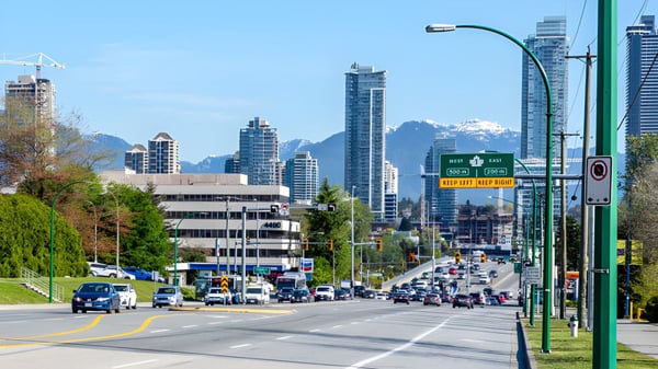 Vista de una calle concurrida con rascacielos y montañas al fondo cerca de la Cariboo Hill School.