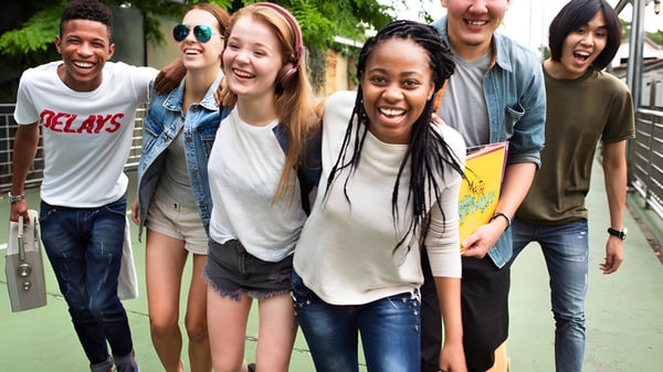 Un grupo de estudiantes de la École secondaire publique Carrefour Jeunesse se encuentra al aire libre frente a un fondo verde.