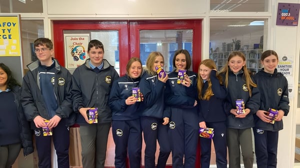 Estudiantes del Carrignafoy Community College están juntos en el pasillo de la escuela con uniforme escolar.