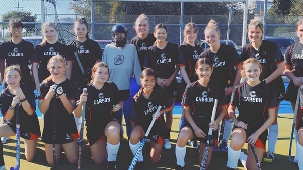 Un grupo de jóvenes atletas posan juntas en el campo deportivo de la Carson Graham Secondary School.
