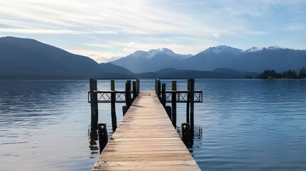 Un muelle de madera conduce en el campus de la Cashmere High School a un lago tranquilo con montañas nevadas de fondo.