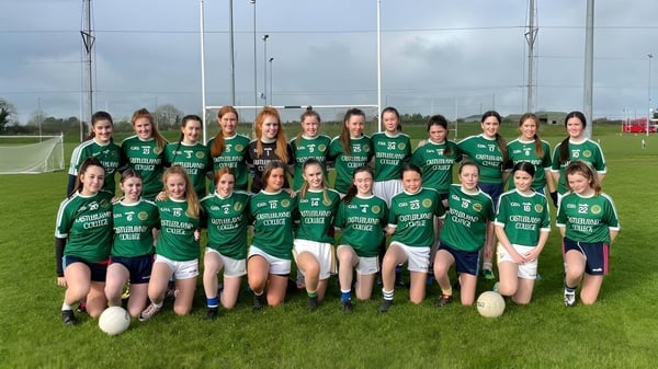 Un grupo de jóvenes futbolistas en camisetas verdes posan juntas en el campo de fútbol de Castleblayney College.