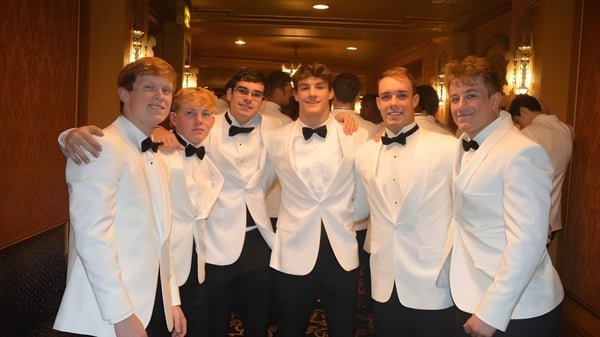 Un grupo de hombres en chaquetas de esmoquin blancas y pajaritas negras en el pasillo de la Cathedral Preparatory School.