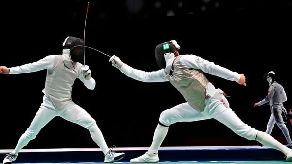 Dos estudiantes de la Cathedral School of St Anne & St James visten uniformes de esgrima blancos y realizan un combate de esgrima.