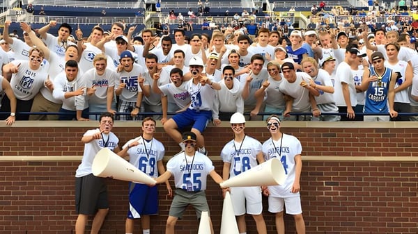 Estudiantes de la Catholic Central High School se reúnen en las gradas del estadio con megáfonos de cheerleading.