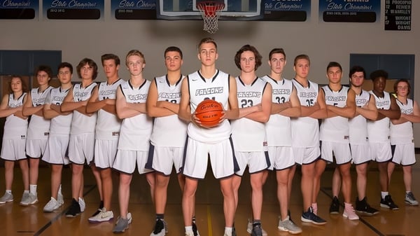 Un grupo de estudiantes del Cave Creek Unified School District están juntos en la cancha de baloncesto con la canasta de fondo.