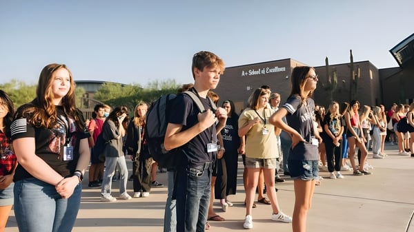 Un grupo de estudiantes está al aire libre frente a edificios en el campus del Cave Creek Unified School District.