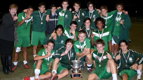 Un grupo de jóvenes atletas celebra con un trofeo en el campus de la Cavendish Road State High School.