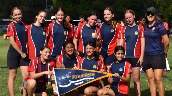 Un grupo de estudiantes de la Centenary State High School posando juntos en un campo deportivo con un banner en primer plano.