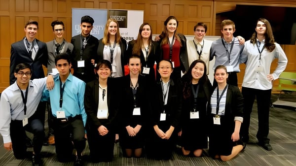 Un grupo de jóvenes adultos en ropa formal posan en una sala de conferencias en el campus del Centennial Collegiate Vocational Institute.