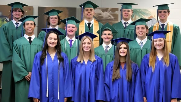 Un grupo de graduados en togas verdes y azules posan en la sala con decoraciones en el campus de la Central Christian School.