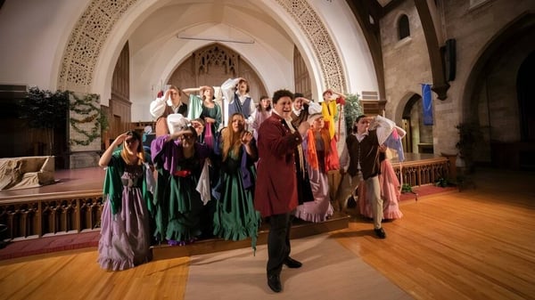 Un grupo de estudiantes de la Central Methodist University está en trajes coloridos en un interior decorado de manera ostentosa con techos abovedados.