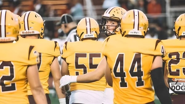 Un grupo de jugadores de fútbol americano de la Central Regional High School está de pie en uniformes amarillos en el campo.