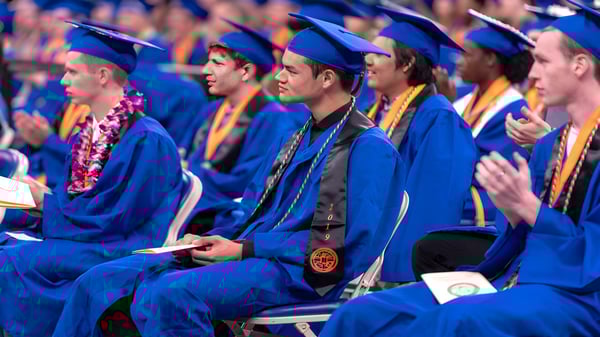 Los graduados de la Chaffey Joint Union High School District están sentados en togas azules durante la ceremonia de graduación en el auditorio.