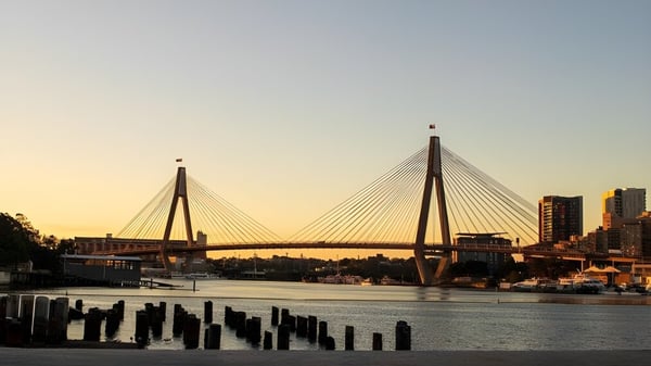 Un puente colgante sobre un río con vista a la ciudad al atardecer cerca del Chancellor State College.