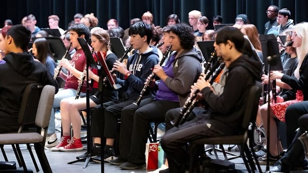 Estudiantes del Chandler Unified School District están sentados en filas tocando diferentes instrumentos musicales durante una prueba de música.