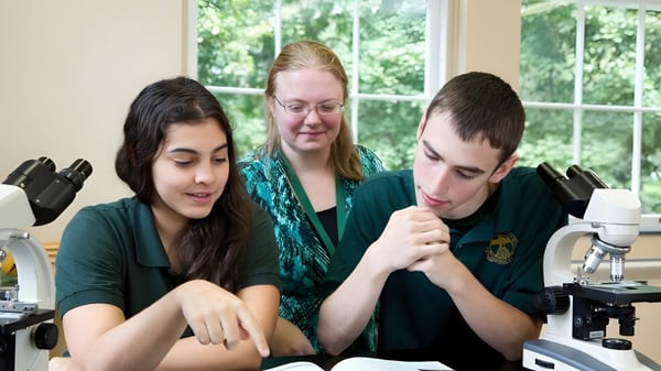 Tres estudiantes están sentados juntos en un aula de The Charles Finney School con vista al entorno verde.
