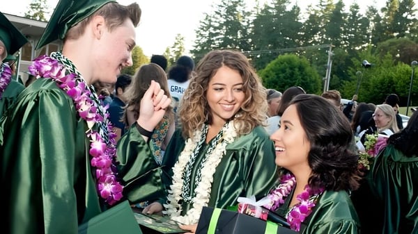 Estudiantes de la Charles Wright Academy celebran al aire libre juntos su graduación en togas verdes y birretes.