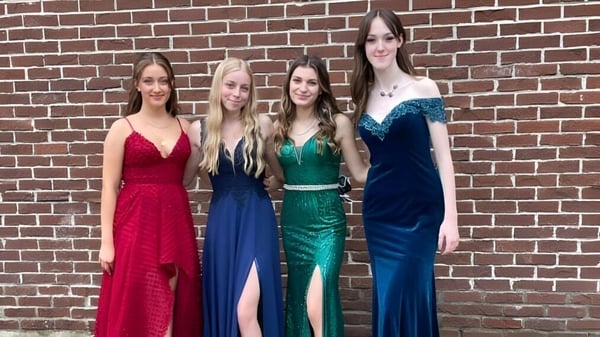 Cuatro estudiantes en ropa formal están frente a una pared de ladrillo en el terreno de la Chateauguay Valley Regional High School.