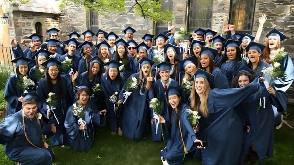 Los graduados de Chapel Hill - Chauncy Hall están en el exterior con togas de graduación azules frente a un edificio de piedra.