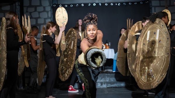 Una estudiante de la Cheshire Academy lleva un traje dorado en una actuación en el escenario con otros intérpretes.