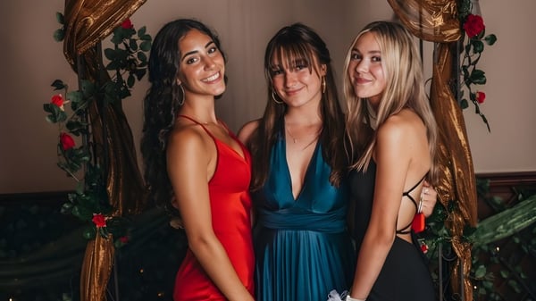 Tres estudiantes de la Cheshire Academy posan juntas frente a un fondo floral.