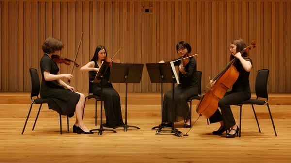 Un cuarteto de cuerda toca en el escenario de la Chetham’s School of Music frente a un revestimiento de madera.