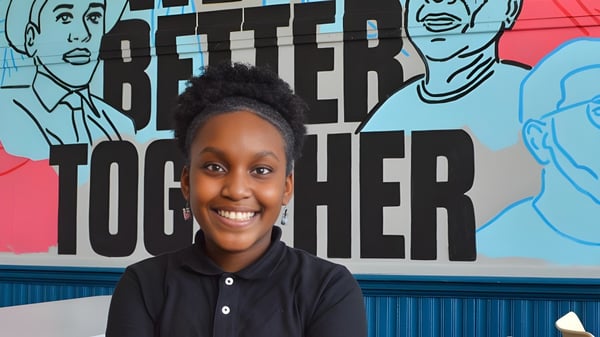 Un joven está frente a un colorido mural con la inscripción 'Better Together' en el terreno de Chicago Public Schools.