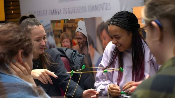Un grupo de estudiantes en el Chichester College trabaja juntos con hilo en una actividad grupal.