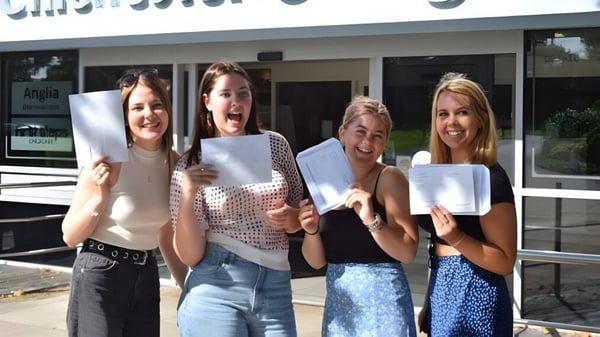 Cuatro estudiantes sosteniendo documentos frente a un edificio del Chichester College.