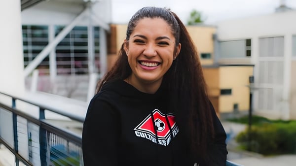 Una estudiante de la Chief Sealth High School está frente a un edificio con un colorido mural.